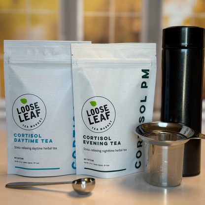The two teas in the Cortisol Tea Bundle with a stainless steel tea scoop, stainless steel tea infuser, and travel tea tumbler.