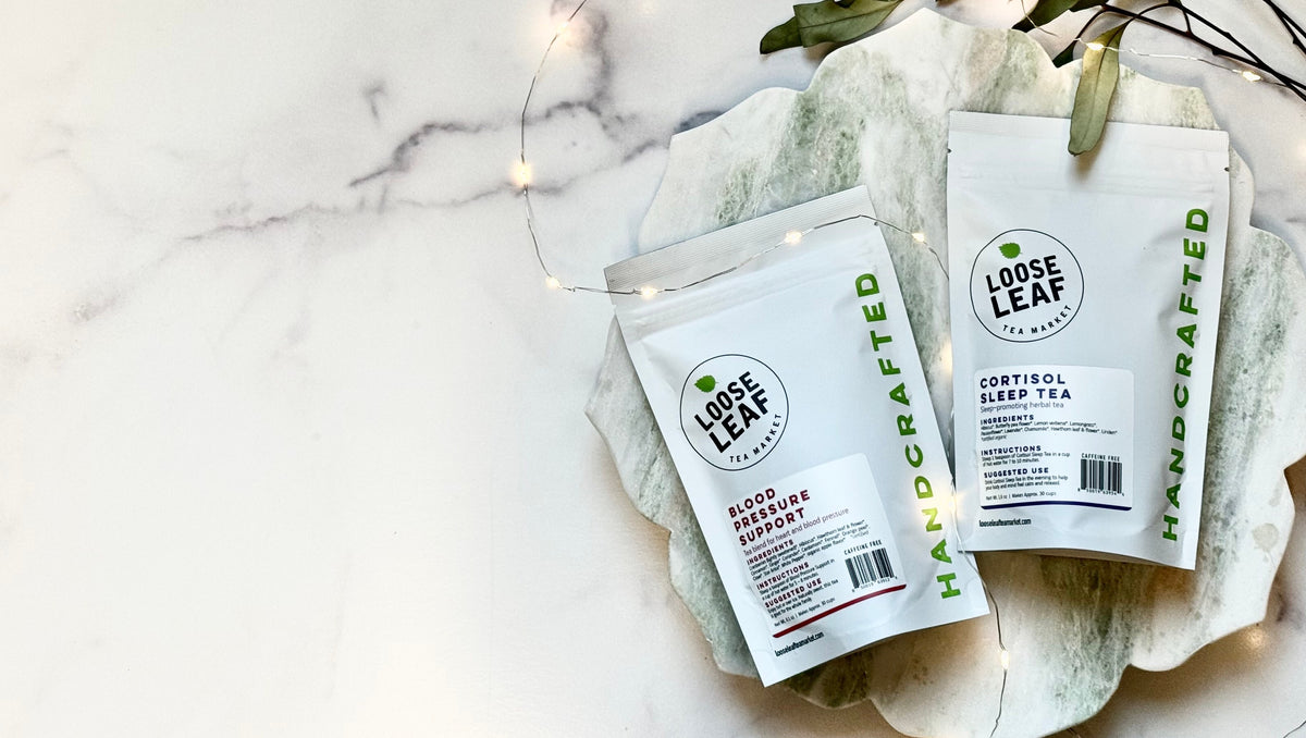 Loose Leaf Tea Market Blood Pressure Support and Cortisol Sleep Tea pouches on a green marble board with fairy lights